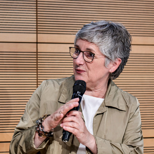 Eine Frau sitzt auf einer Bühne und spricht in ein Mikrofon