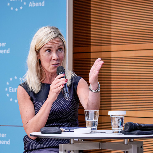 Eine Frau sitzt auf einer Bühne und spricht in ein Mikrofon