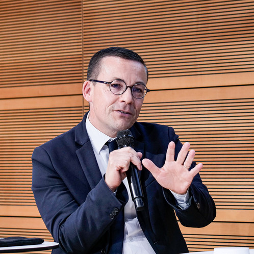 Ein Mann sitzt auf einer Bühne und spricht in ein Mikrofon