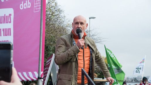 Ein Mann steht vor einer Gruppe Menschen und spricht in ein Mikrofon