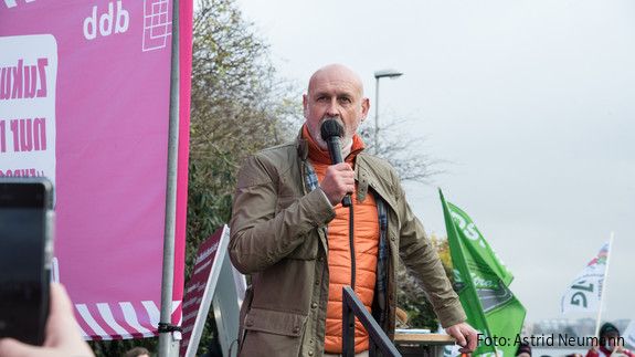 Ein Mann steht vor einer Gruppe Menschen und spricht in ein Mikrofon