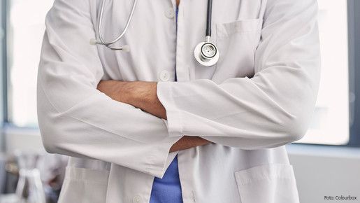 Das Foto zeigt einen Arzt, er hat die Arme verschränkt.