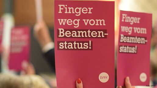 Eine Gruppe Menschen hält Schilder mit der Aufschrift "Finger weg vom Beamtenstatus" hoch