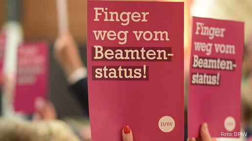 Eine Gruppe Menschen hält Schilder mit der Aufschrift "Finger weg vom Beamtenstatus" hoch
