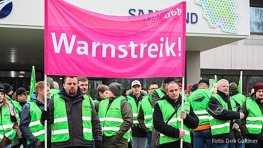 Das Foto zeigt demonstrierende Straßenwärter. Sie tragen grüne Streikwesten.