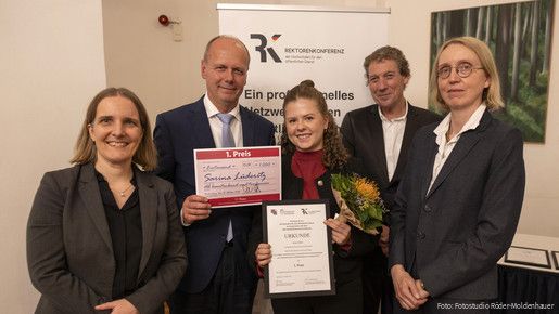 Fünf Menschen halten eine Urkunde für den ersten Platz und blicken in die Kamera