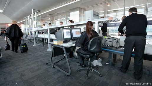 Das Bild zeigt Mitarbeitende des Sicherheitspersonals bei der Sicherheitskontrolle am Flughafen.