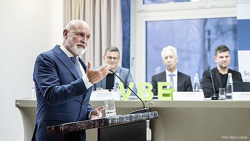 Ein Mann steht hinter einem Rednerpult und spricht in ein Mikrofon