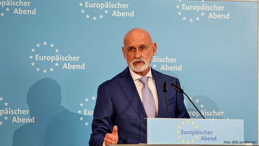 Ein Mann in Anzug steht hinter einem Rednerpult und spricht in das Mikrofon.