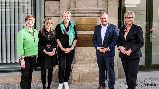 Fünf Menschen stehen vor einem Gebäudeeingang